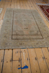 Vintage distressed Oushak rug with central medallion detail in muted apricot and beige.