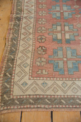 Distressed vintage Oushak rug corner with blush, ivory, and blue geometric border details.