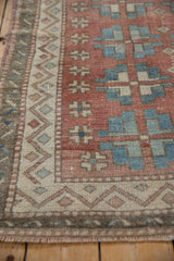 Distressed Oushak rug with a zig-zag border and geometric guls in pale red, blue, and ivory.