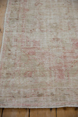 Vintage distressed Oushak rug with worn pile, visible foundation, and muted pink on ivory.