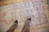 Worn vintage Oushak runner in raspberry red and ivory, with foundation showing through the distressed low pile.