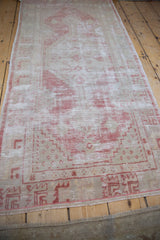 Perspective view of a distressed Oushak runner highlighting its soft, worn texture and pale hues.