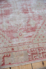 Detailed texture of a distressed Oushak rug with pale raspberry red and ivory threads worn to the foundation.