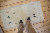 Distressed vintage Tulu runner pile underfoot, with primitive red, blue, and green motifs.