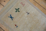 Corner of vintage distressed Tulu rug, showing shaggy cream pile and blue primitive motif.
