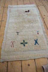 Red primitive motif on cream textured pile of this vintage distressed Tulu rug.