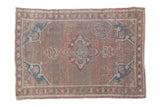 Distressed Anatolian rug with dusty mauve rose and sapphire blue motifs, showing foundation wear.