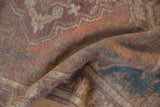 Distressed vintage Anatolian rug's worn pile texture with muted mauve and blue tones.