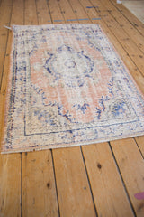 Angled view of a hand-knotted Oushak rug showing its heavy, decorative distress.