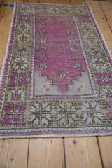 Low angle perspective on a vintage distressed Oushak rug highlighting its purple prayer design.