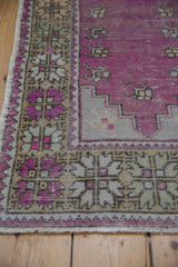 Worn pile on the purple stepped mehrab and palmette border of a distressed Oushak rug.