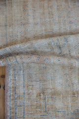 Textured view of distressed Oushak rug showing exposed foundation, beige and pale blue.