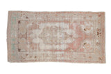 Distressed Oushak rug runner with a large medallion in faded dusty rose, ivory, and pale ocean blue.