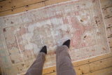 Vintage distressed Oushak rug viewed underfoot, showing its soft color palette and worn texture.