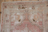 Time-worn corner of a vintage Oushak rug in dusty rose, showing the exposed foundation.