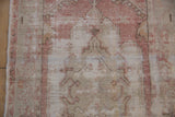 Exposed foundation and worn knot heads on a distressed Oushak rug with dusty rose and ivory tones.