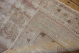 Hand-knotted foundation and distressed, faded pile visible on a folded corner of an Oushak rug.
