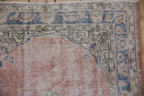 Corner of distressed Sparta runner with Rococo border, blush field, dusty cobalt, and exposed foundation.