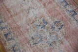 Textured view of distressed vintage Sparta rug showing foundation, blush, cobalt, and beige Rococo motifs.