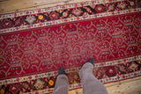 Angled view of a vintage Anatolian runner's cherry red field, highlighting its samovar panel design.