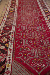 Low angle view of the vintage Anatolian runner showing the textured red trellis pattern and side borders.