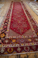 Angled perspective of a vintage Anatolian runner showing its full length and repeating cherry red samovar pattern.