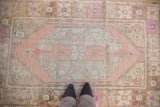 Distressed Oushak rug detail: faded pink hexagonal medallion with varied pile texture.