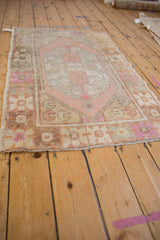 Distressed vintage Oushak rug edge with muted pink, oxidized silver, and gold geometric florals.