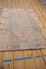 Pale pink distressed pile texture and secured edge of a vintage Oushak rug corner.