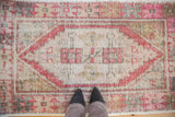 Distressed Oushak rug detail: brick red stepped medallion, geometric palmettes, worn pile, and feet.