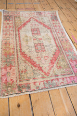 Distressed Oushak rug with prominent brick red geometric designs, ivory field, and textured surface.