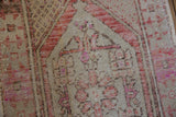 Distressed Oushak texture with low pile, visible foundation, and muted rust-pink motifs.