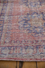 Distressed Oushak rug texture showing faded pink, cobalt blue, and beige, with exposed knot heads.