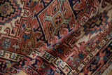 Folded texture of vintage Karaja rug showcasing hand-knotted geometric patterns in brick red, navy, ivory.