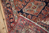 Vintage Karaja rug corner folded, showcasing geometric pattern, hand-knotted foundation, and creamy fringe.