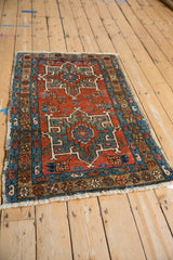 Brick red Karaja rug corner with serrated palmette medallions, floral main border, and fringe.