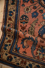 Folded detail of the vintage Mehreban rug, showing dusty blush, sapphire, and copper serrated leaves.