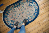 Corner of Art Deco rug with cobalt blue border and elaborate blush blossoms.