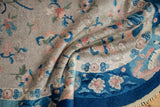 Folded pile of an Art Deco rug, revealing cobalt blue border and dusty blush floral motifs.