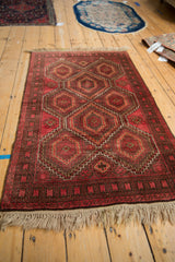 Vintage Belouch rug detail: raspberry red geometric guls, serrated contours, coffee brown border.