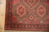 Raspberry red guls and coffee brown serpent border on vintage Belouch rug corner.