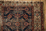 Vintage Hamadan rug detail: navy Herati motif, rust henna border, worn pile, tattered fringe.