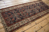 Tattered end and frayed selvage of a vintage Hamadan runner, showing henna plant border.