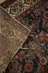 Detail of vintage Hamadan runner showing dark navy Herati pattern, foundation wear, and frayed selvage.