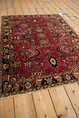 Vintage Sarouk rug's cherry red field with oversized palmettes, vines, and black border.