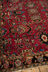 Vintage Sarouk rug's cherry red field, sapphire palmettes, black and blue arabesques, textured pile.