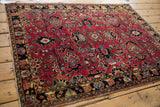 Vintage Sarouk rug corner detail: cherry red field, blue palmettes, and tattered border.