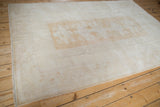 Distressed vintage Melas carpet with faded geometric border and subtle ivory field design.
