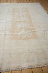 Distressed Melas carpet pile, displaying ivory, pale gold tones, geometric relief, and fringe.