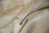 Distressed pile texture of a vintage Melas carpet in faded ivory, cream, and pale gold.